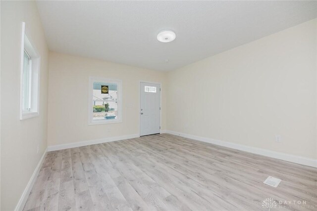interior space with light wood-style floors, a wealth of natural light, and baseboards