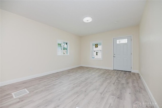 interior space with baseboards, visible vents, light wood finished floors, and a wealth of natural light