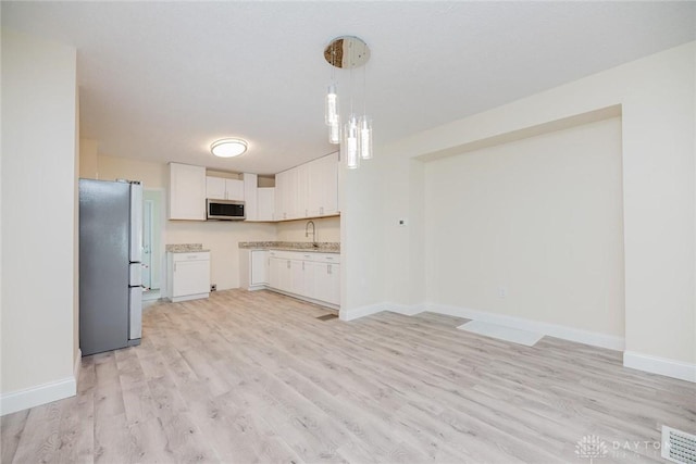 kitchen featuring white cabinetry, light wood finished floors, baseboards, and stainless steel appliances
