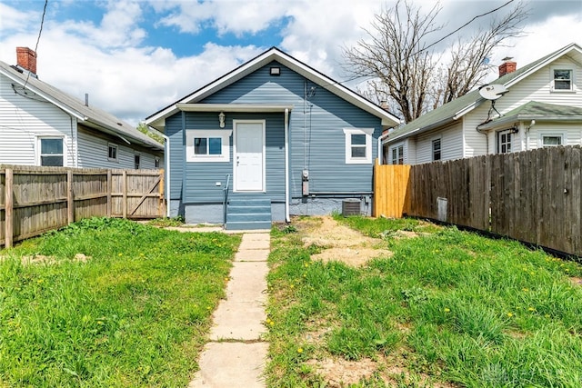 rear view of property with entry steps, a lawn, and a fenced backyard