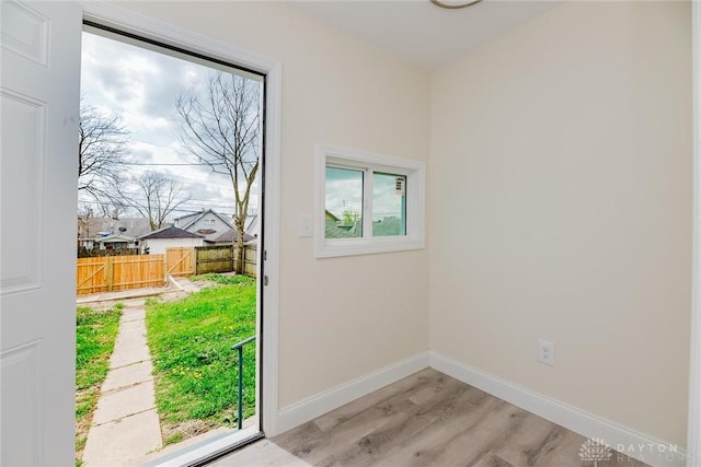doorway with light wood-type flooring, baseboards, and a healthy amount of sunlight