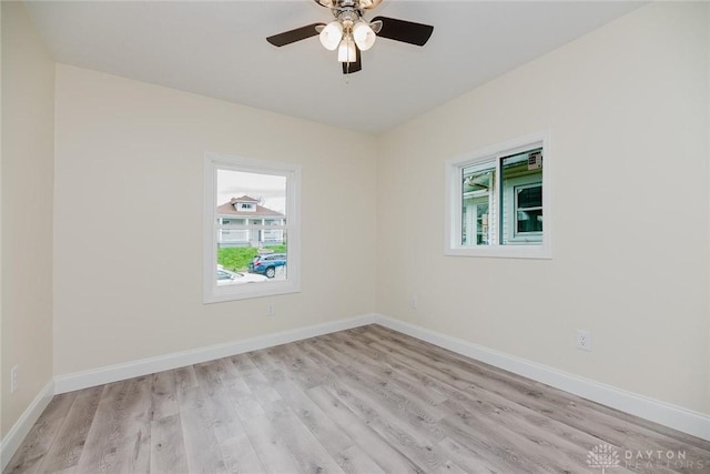 spare room featuring light wood-type flooring, a healthy amount of sunlight, a ceiling fan, and baseboards