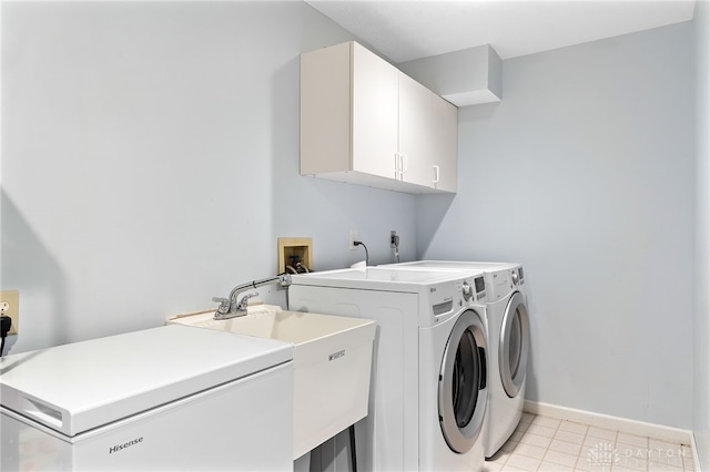 washroom featuring washing machine and clothes dryer, a sink, light tile patterned floors, cabinet space, and baseboards