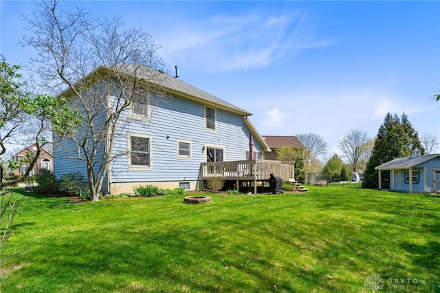 rear view of property featuring an outdoor fire pit, a yard, and a deck