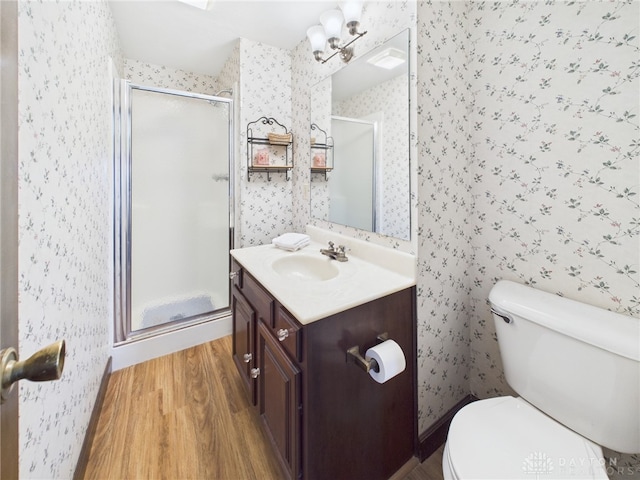 bathroom featuring a shower stall, wood finished floors, wallpapered walls, vanity, and toilet