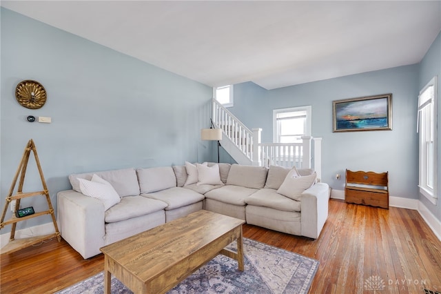 living room featuring hardwood / wood-style flooring, baseboards, and stairs