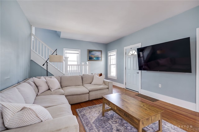 living room featuring stairs, wood finished floors, and baseboards