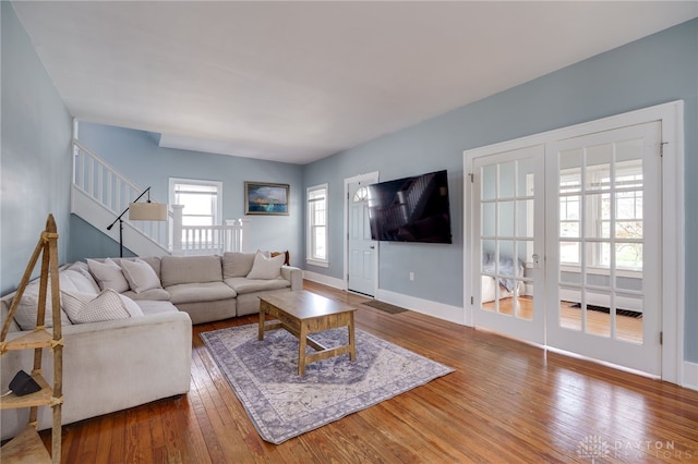 living area with baseboards, stairs, and wood-type flooring