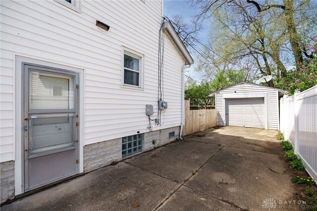 view of home's exterior featuring an outdoor structure, a garage, concrete driveway, and fence