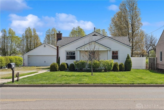 view of front of property featuring fence, a chimney, a front yard, and a detached garage