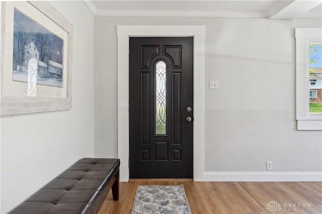 entryway with wood finished floors, baseboards, and ornamental molding