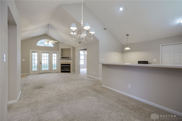 unfurnished living room with baseboards, light colored carpet, lofted ceiling, ceiling fan with notable chandelier, and a fireplace