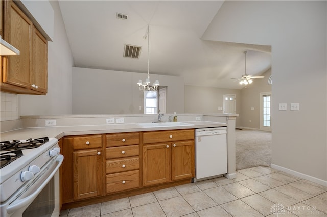 kitchen with a peninsula, a sink, vaulted ceiling, white appliances, and brown cabinets