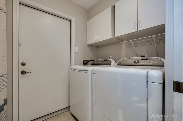 laundry area with washer and dryer, light tile patterned floors, and cabinet space