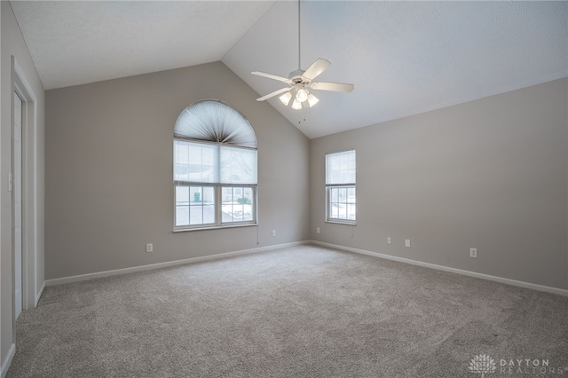 empty room with high vaulted ceiling, carpet floors, a ceiling fan, and baseboards