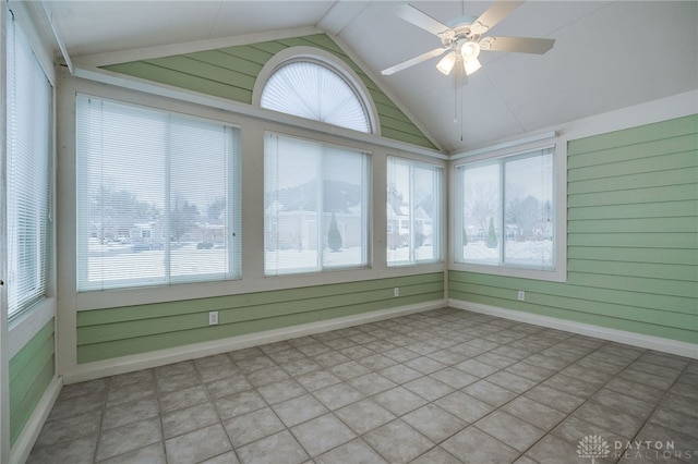 unfurnished sunroom with vaulted ceiling, wood walls, and baseboards