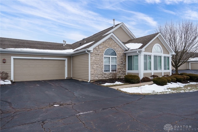 view of front of property featuring a garage, stone siding, aphalt driveway, and a shingled roof