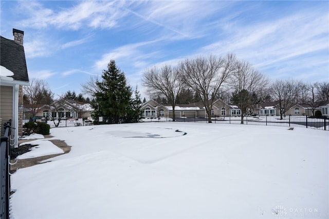 yard layered in snow with fence and a residential view