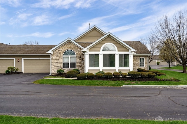 ranch-style house featuring stone siding, a shingled roof, driveway, and a garage