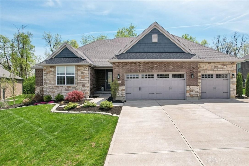 craftsman inspired home featuring a shingled roof, concrete driveway, stone siding, a front yard, and a garage