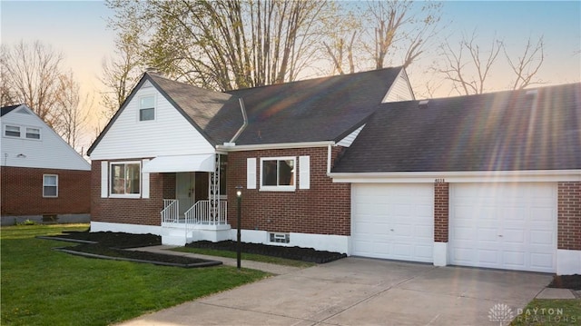 view of front of home featuring a shingled roof, a yard, concrete driveway, an attached garage, and brick siding