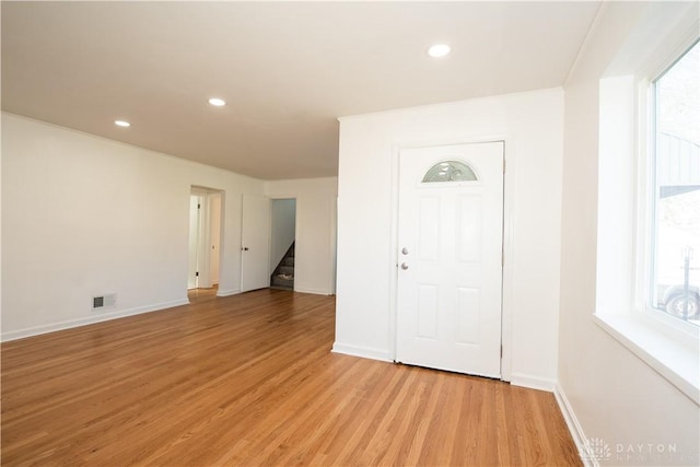 foyer entrance featuring visible vents, light wood finished floors, stairs, and a wealth of natural light