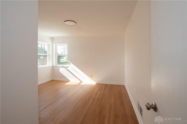 unfurnished room featuring wood finished floors, visible vents, and baseboards
