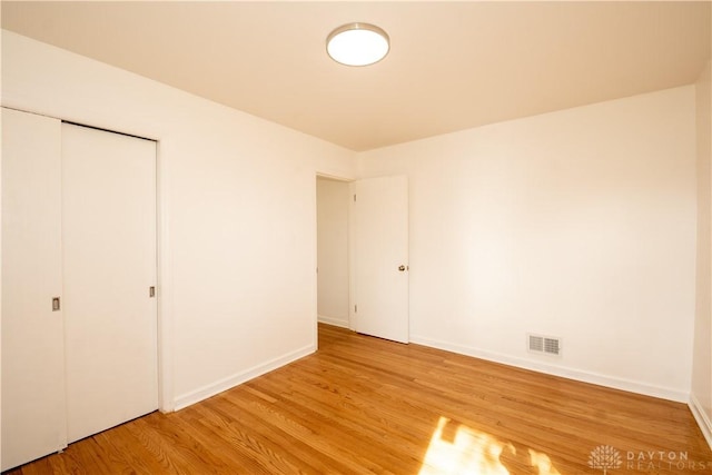 unfurnished bedroom with visible vents, light wood finished floors, and baseboards