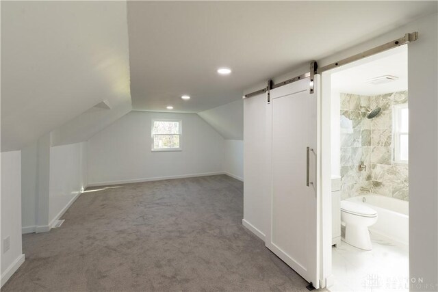 additional living space featuring a barn door, vaulted ceiling, carpet flooring, and baseboards