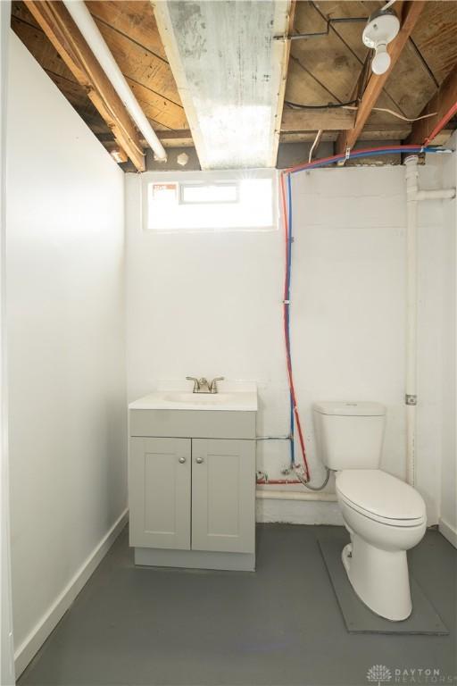 bathroom with concrete floors, toilet, vanity, and baseboards