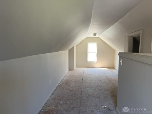 additional living space featuring vaulted ceiling, carpet flooring, and baseboards