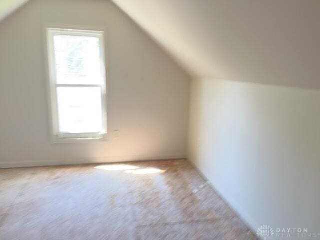 bonus room with vaulted ceiling, plenty of natural light, and carpet flooring