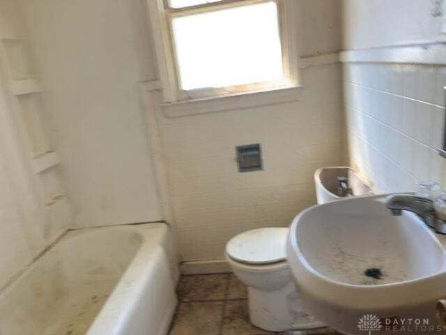 full bath with tile patterned flooring, tile walls, toilet, and a sink