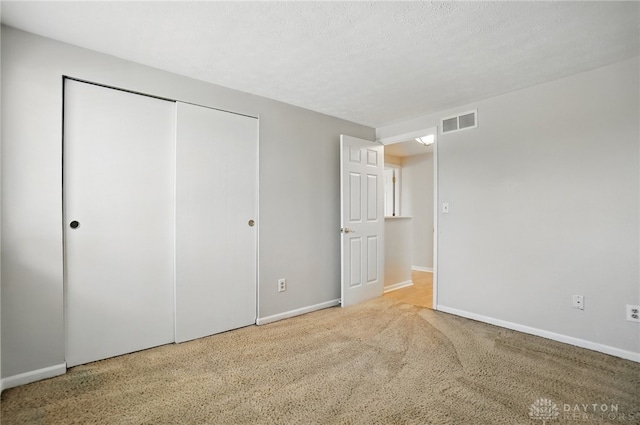 unfurnished bedroom featuring baseboards, a closet, visible vents, and carpet