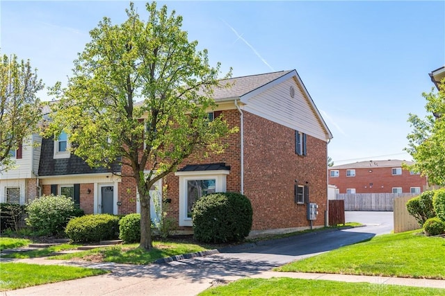 view of front of property with fence, driveway, a front lawn, and brick siding