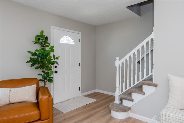 entryway with baseboards, wood finished floors, and stairs