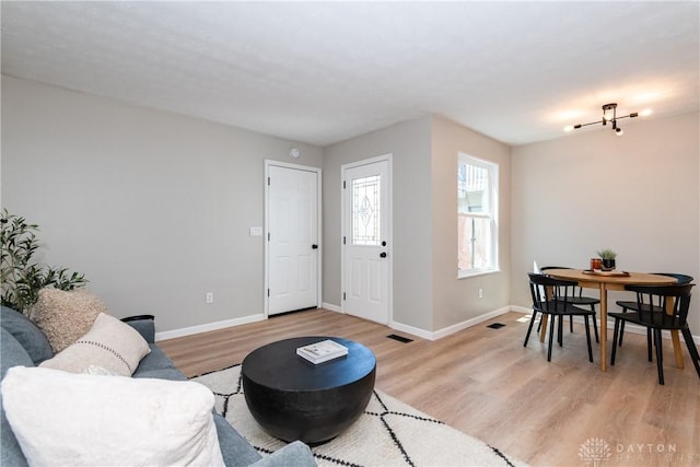 living area with baseboards, visible vents, and light wood finished floors