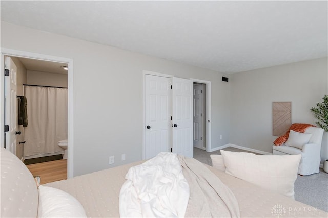 bedroom with visible vents, light carpet, and ensuite bathroom