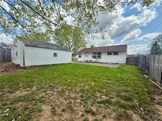 back of property with a yard, an outbuilding, and fence