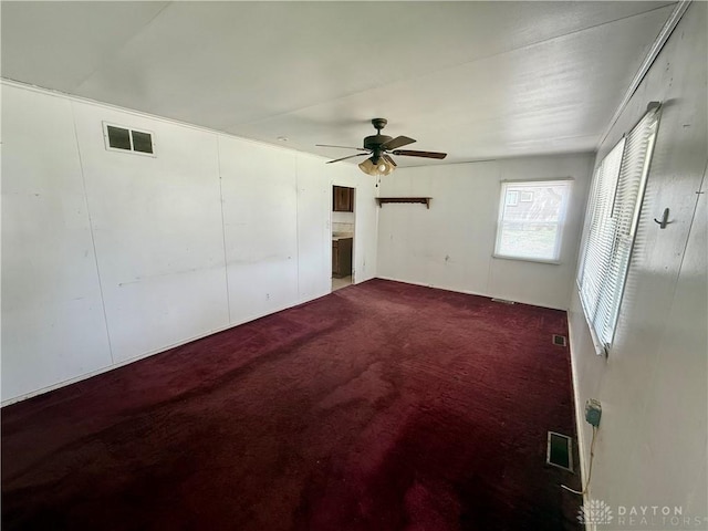 unfurnished bedroom featuring visible vents, dark carpet, and ceiling fan