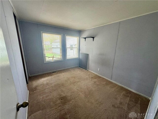 carpeted empty room with visible vents, baseboards, and ornamental molding