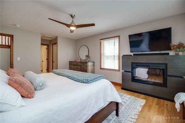 9171 Big Oak Dr, Washington Twp, OH 45458 - bedroom with wood finished floors, a ceiling fan, and a glass covered fireplace