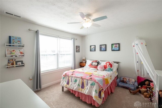 bedroom with ceiling fan, visible vents, a textured ceiling, and light colored carpet