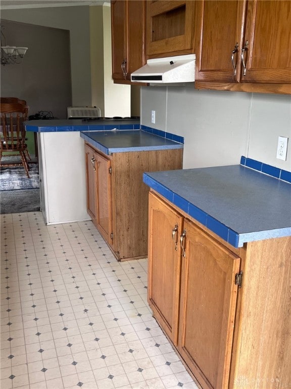 14384 NW US Highway 35, Jeffersonville, OH 43128 - kitchen featuring under cabinet range hood, a peninsula, brown cabinetry, and light flooring