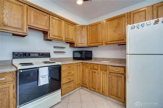 kitchen featuring black microwave, light countertops, freestanding refrigerator, light tile patterned flooring, and electric range oven