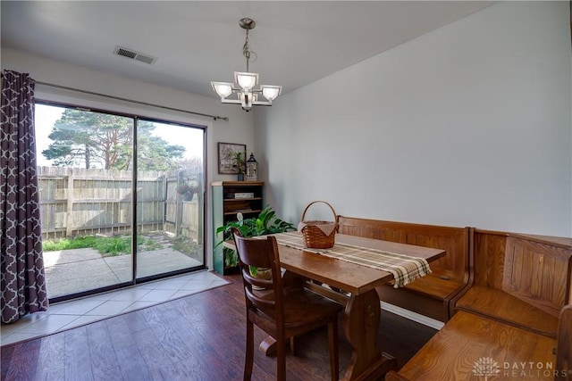 dining room with visible vents, wood finished floors, and an inviting chandelier