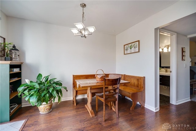 dining space with baseboards, a notable chandelier, and wood finished floors