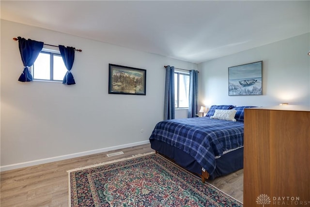 bedroom with visible vents, wood finished floors, and baseboards
