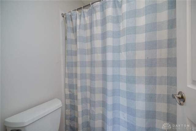 full bathroom featuring a shower with shower curtain and toilet