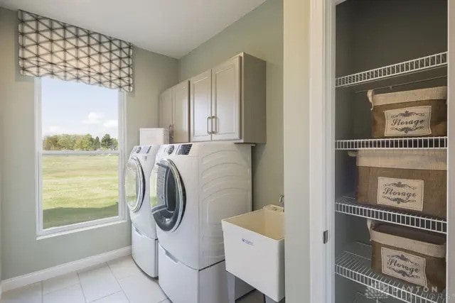 laundry room featuring baseboards, washer and clothes dryer, a sink, cabinet space, and light tile patterned floors